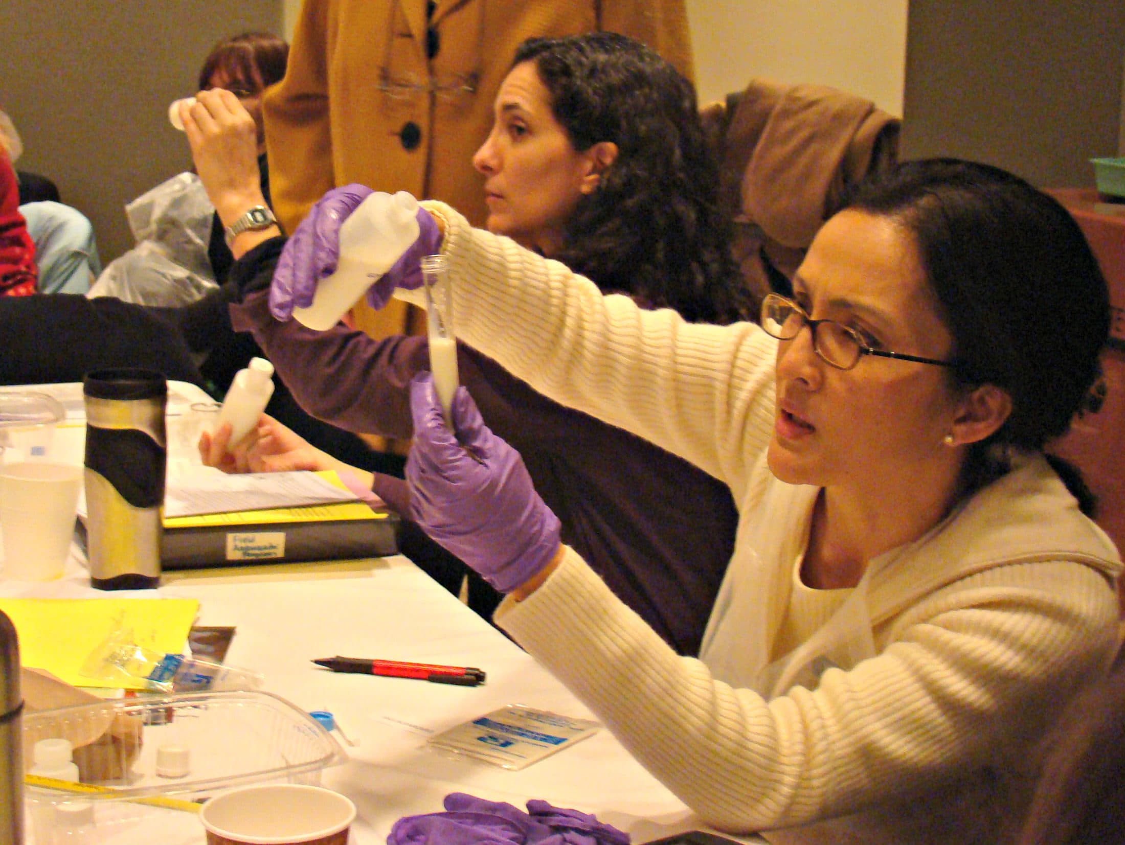 A woman pours a substance into a test tube.