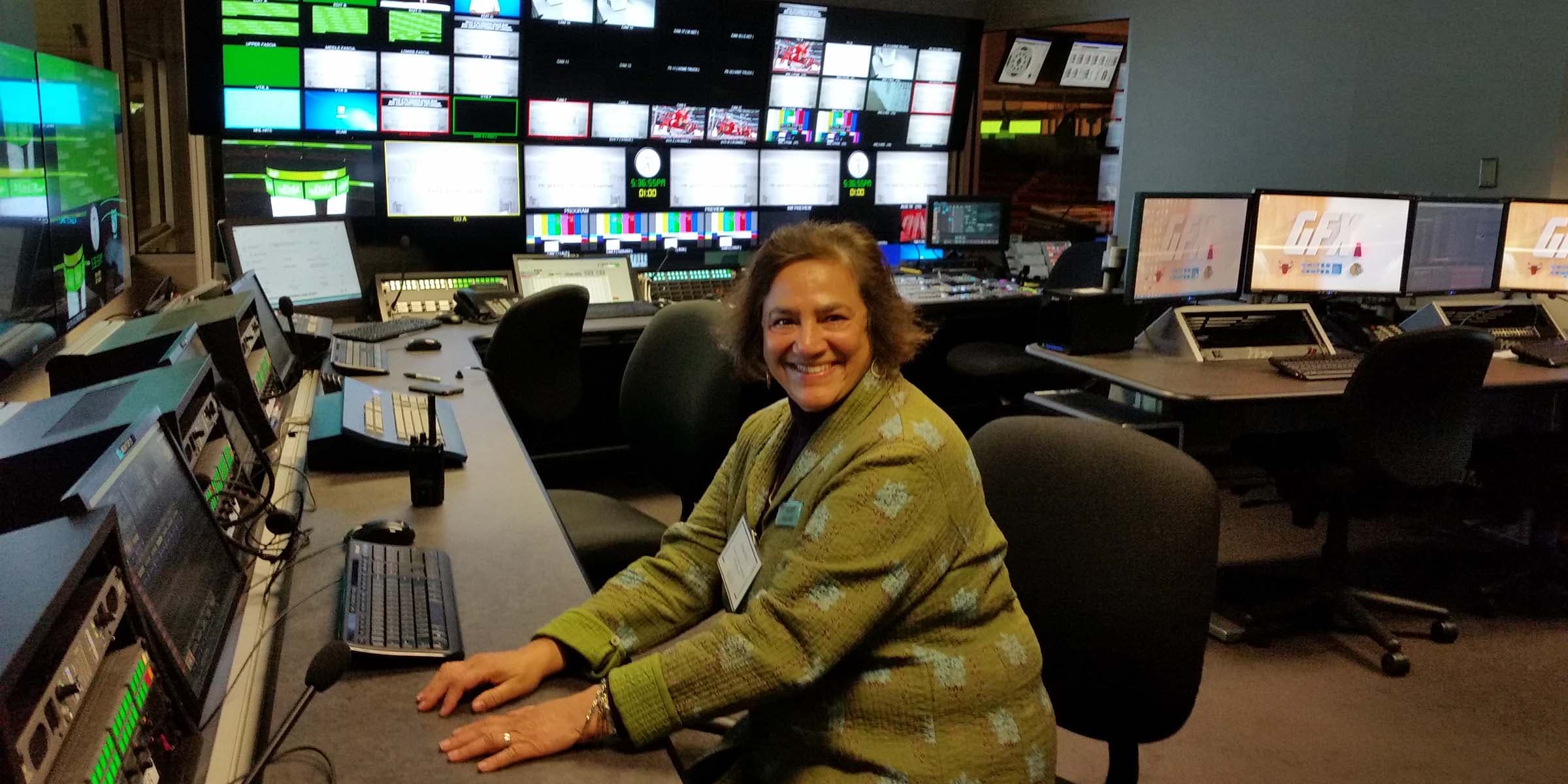 A woman sitting at a dashboard in front of many computer screens